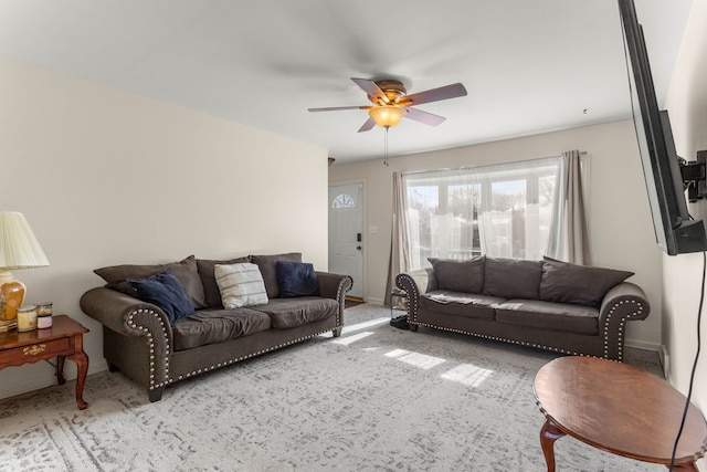 carpeted living room with baseboards and a ceiling fan