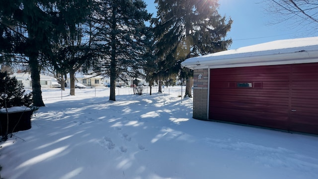 yard layered in snow featuring fence and an outdoor structure