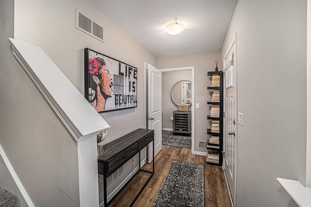 hall with dark wood-type flooring, beverage cooler, visible vents, and baseboards