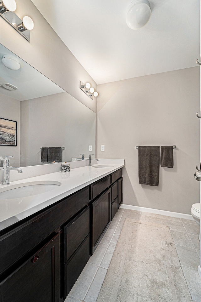 full bath featuring double vanity, a sink, and baseboards