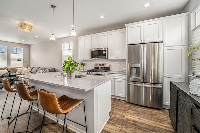 kitchen with dark wood-style floors, a kitchen bar, appliances with stainless steel finishes, and a wealth of natural light