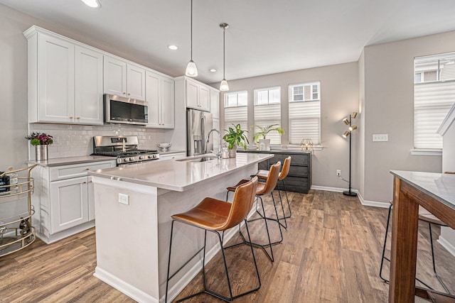 kitchen with wood finished floors, appliances with stainless steel finishes, a sink, and tasteful backsplash