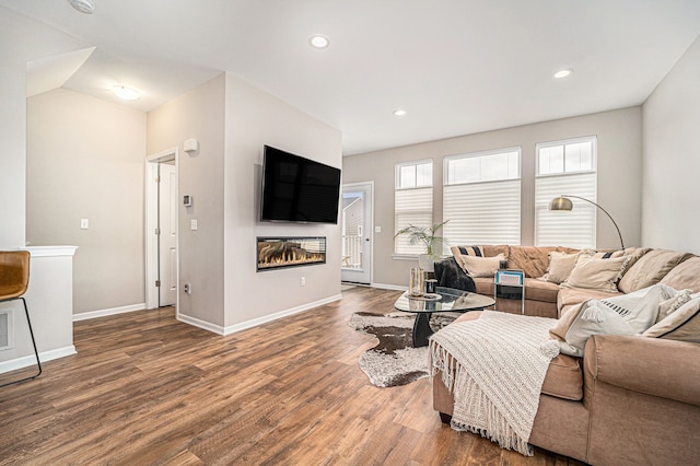 living area featuring wood finished floors, recessed lighting, a glass covered fireplace, and baseboards