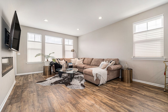 living area featuring recessed lighting, baseboards, wood finished floors, and a glass covered fireplace