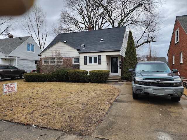 view of front of property featuring entry steps, a chimney, and brick siding