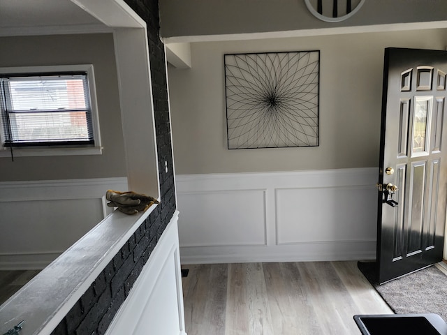 interior space featuring ornamental molding, wainscoting, and wood finished floors