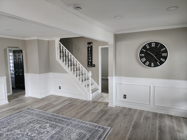 interior space featuring ornamental molding, stairway, wainscoting, and wood finished floors