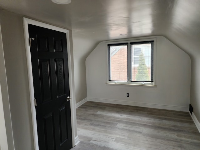 bonus room featuring lofted ceiling, light wood-style floors, and baseboards