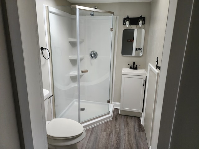 full bathroom with a stall shower, vanity, toilet, and wood finished floors