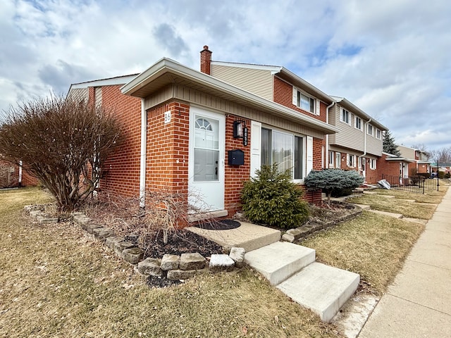 view of front of home with a chimney and brick siding