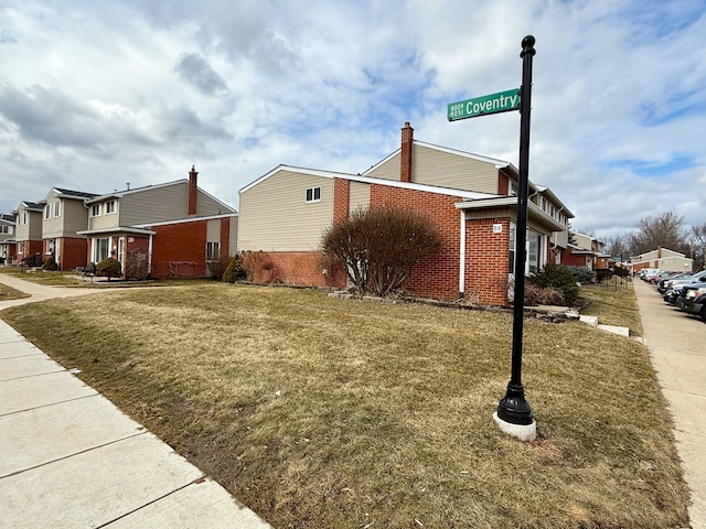 view of home's exterior with a yard, a residential view, and brick siding