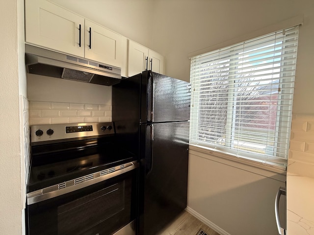 kitchen featuring under cabinet range hood, white cabinetry, freestanding refrigerator, tasteful backsplash, and stainless steel range with electric stovetop