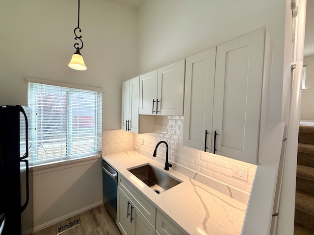 kitchen featuring a sink, visible vents, stainless steel dishwasher, backsplash, and freestanding refrigerator