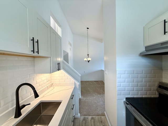 kitchen with hanging light fixtures, light stone countertops, a sink, stainless steel electric stove, and backsplash