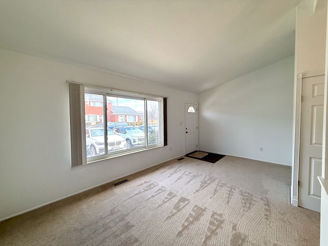 unfurnished room with light colored carpet, vaulted ceiling, and visible vents