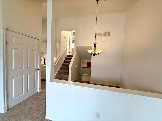 staircase featuring an inviting chandelier, carpet, and visible vents