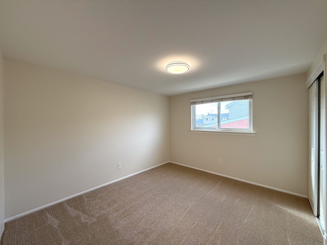 carpeted spare room featuring baseboards