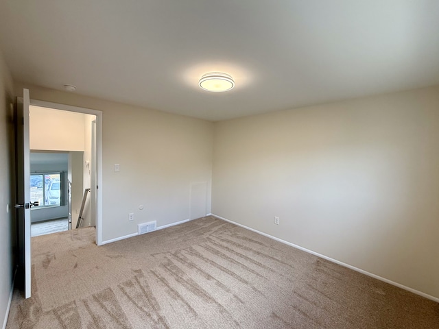 empty room featuring carpet floors, visible vents, and baseboards