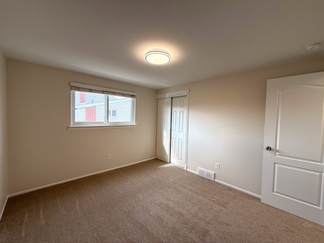 unfurnished bedroom with carpet floors, a closet, visible vents, and baseboards