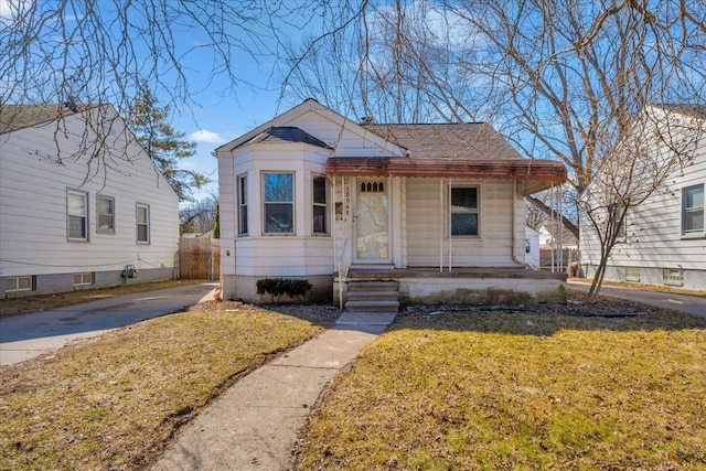 bungalow-style house with a front lawn, roof with shingles, and fence