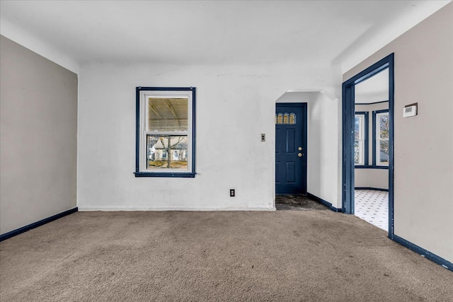 carpeted spare room featuring a healthy amount of sunlight and baseboards