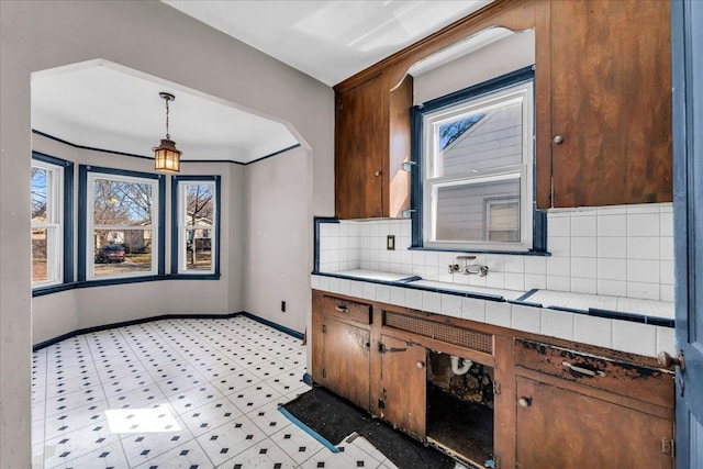 kitchen with tile counters, a healthy amount of sunlight, baseboards, and tasteful backsplash