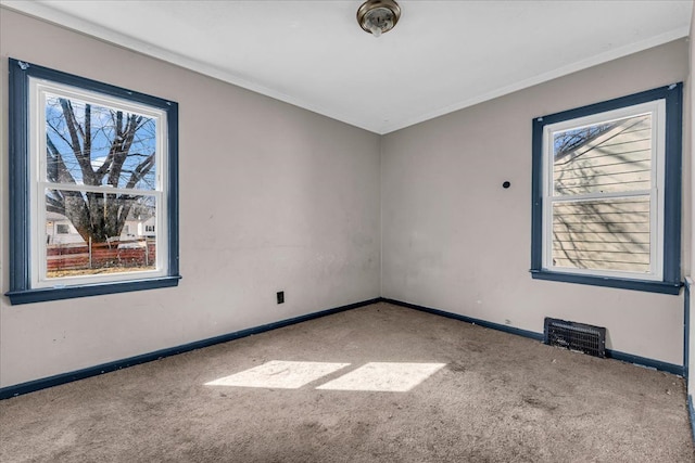 unfurnished room featuring a healthy amount of sunlight, visible vents, and carpet flooring