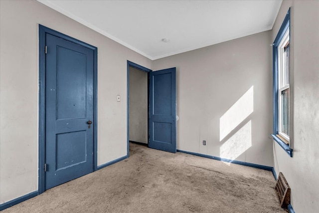 unfurnished bedroom featuring ornamental molding, carpet, visible vents, and baseboards