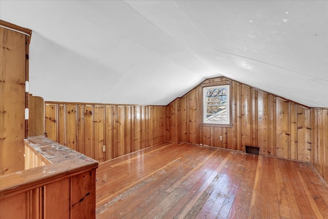 bonus room with vaulted ceiling, hardwood / wood-style flooring, and wooden walls