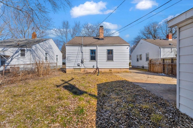 back of house with a chimney and fence