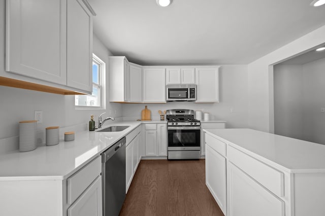 kitchen with dark wood finished floors, light countertops, appliances with stainless steel finishes, white cabinets, and a sink