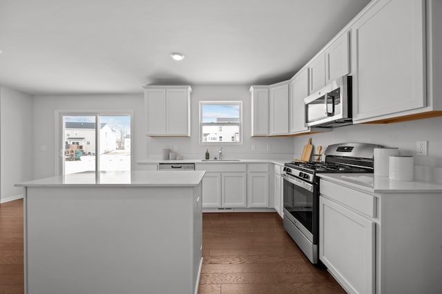 kitchen featuring stainless steel appliances, a kitchen island, dark wood-type flooring, and light countertops