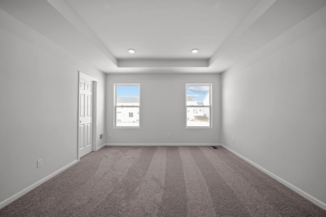 carpeted spare room with recessed lighting, a tray ceiling, and baseboards