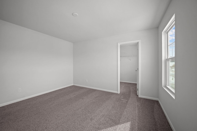 unfurnished room featuring baseboards and dark carpet