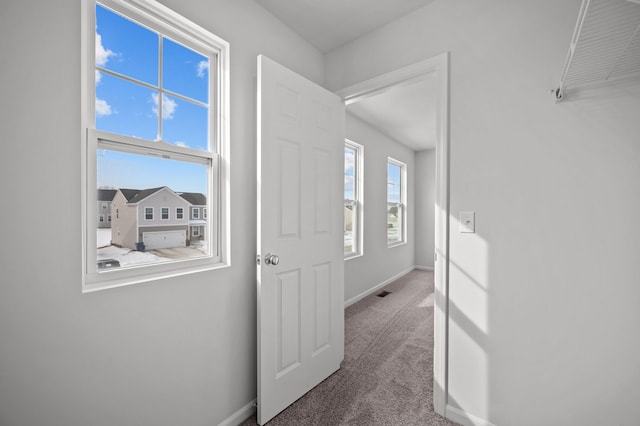 corridor featuring carpet flooring, visible vents, and baseboards