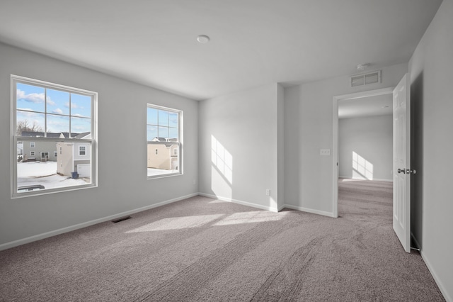 empty room featuring visible vents, baseboards, and carpet flooring