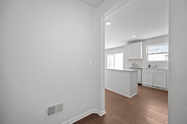 kitchen with visible vents, baseboards, dark wood-style flooring, white cabinetry, and a sink