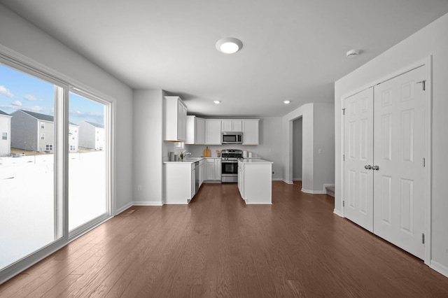 kitchen with baseboards, stainless steel appliances, dark wood-type flooring, light countertops, and white cabinetry