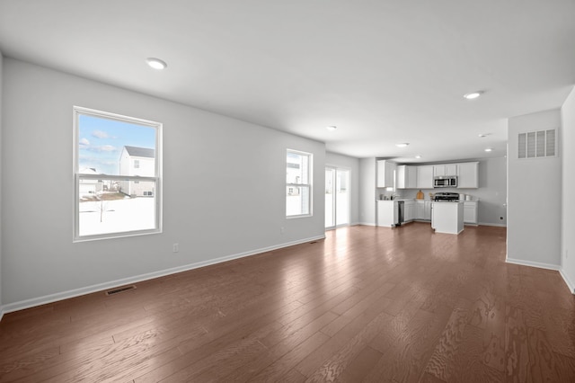 unfurnished living room with recessed lighting, visible vents, baseboards, and dark wood finished floors