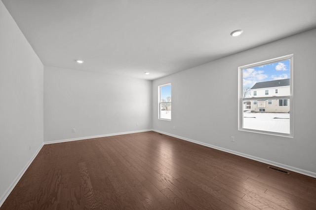 unfurnished room featuring dark wood-style floors, visible vents, recessed lighting, and baseboards