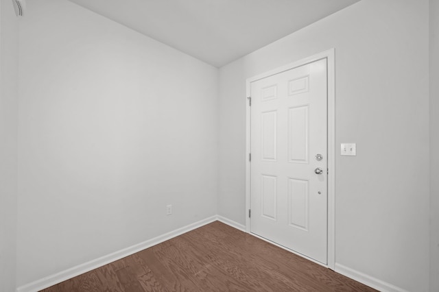 empty room featuring baseboards and dark wood-style flooring