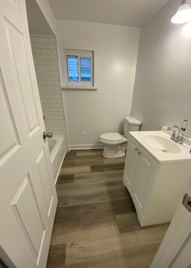 bathroom featuring toilet, vanity, baseboards, and wood finished floors