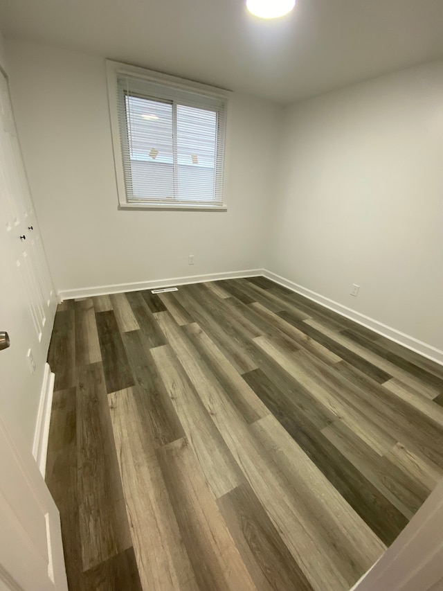 empty room featuring baseboards and dark wood-style floors