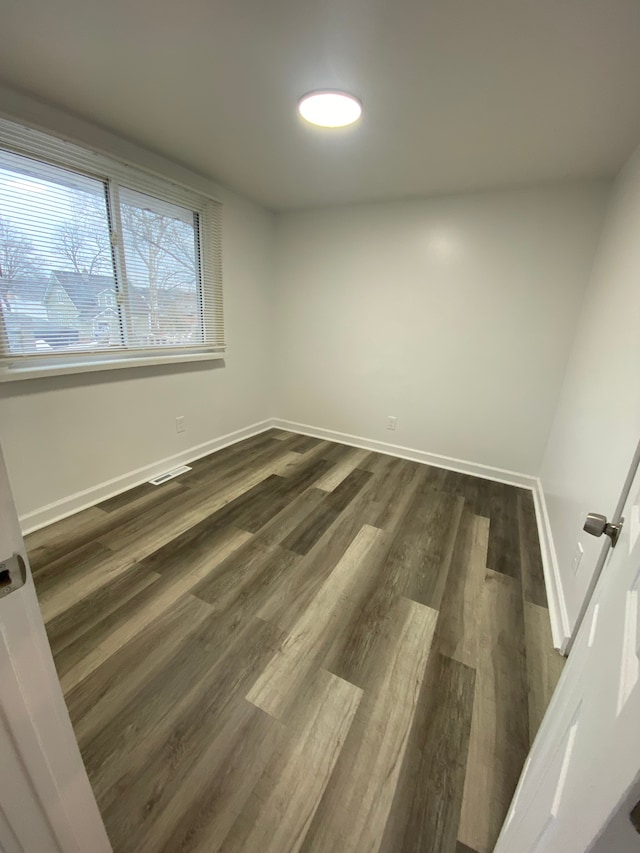 empty room featuring baseboards and dark wood-style floors