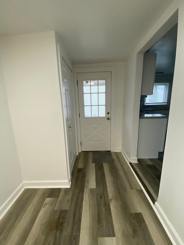 doorway featuring dark wood-style floors and baseboards