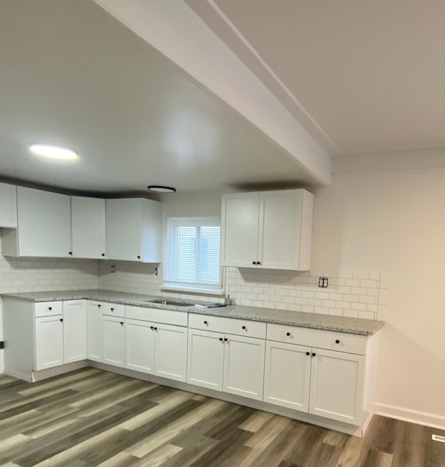 kitchen with light stone counters, a sink, white cabinetry, decorative backsplash, and dark wood-style flooring