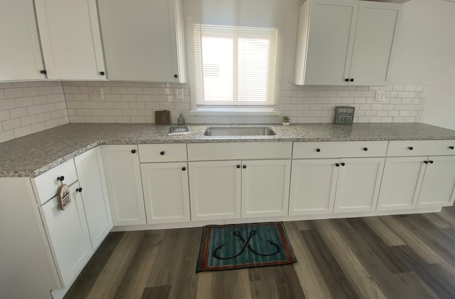 kitchen featuring backsplash, dark wood finished floors, light stone counters, white cabinets, and a sink