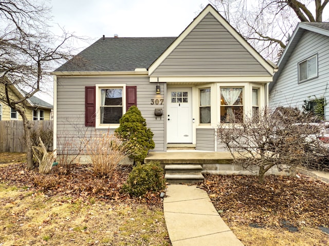 bungalow featuring a shingled roof and fence