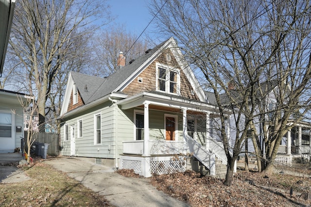 view of front of property with a shingled roof, a porch, and a chimney