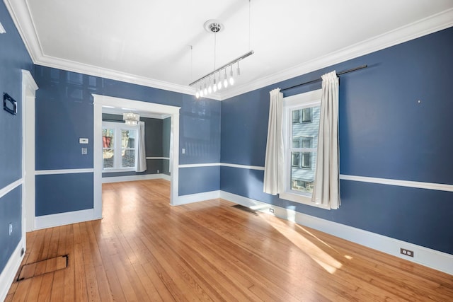 spare room featuring visible vents, baseboards, ornamental molding, and hardwood / wood-style flooring